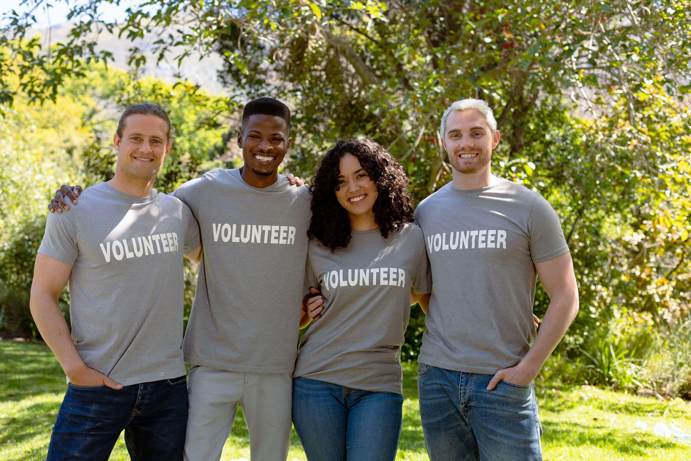 four people in volunteer t-shirts, arm in arm, smiling
