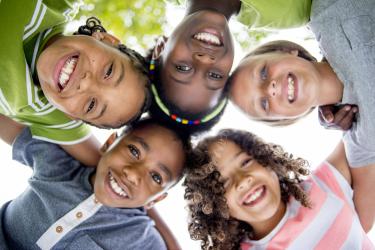 five kids in a huddle smiling down on the camera