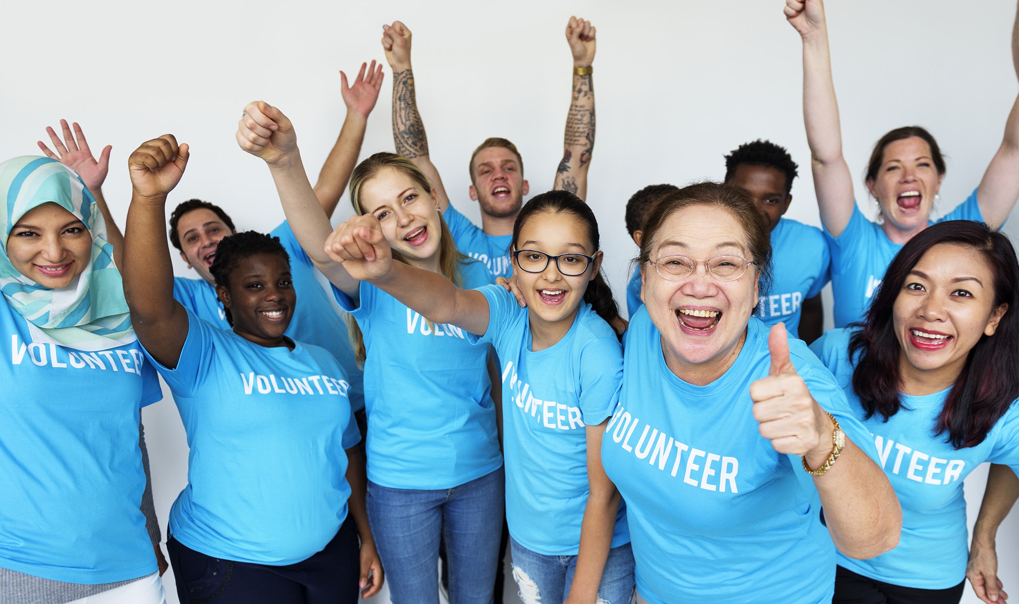a group of people wearing volunteer t-shirts, cheering and smiling