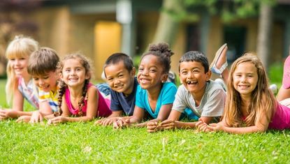 kids lying in a row in the grass, happy and healthy