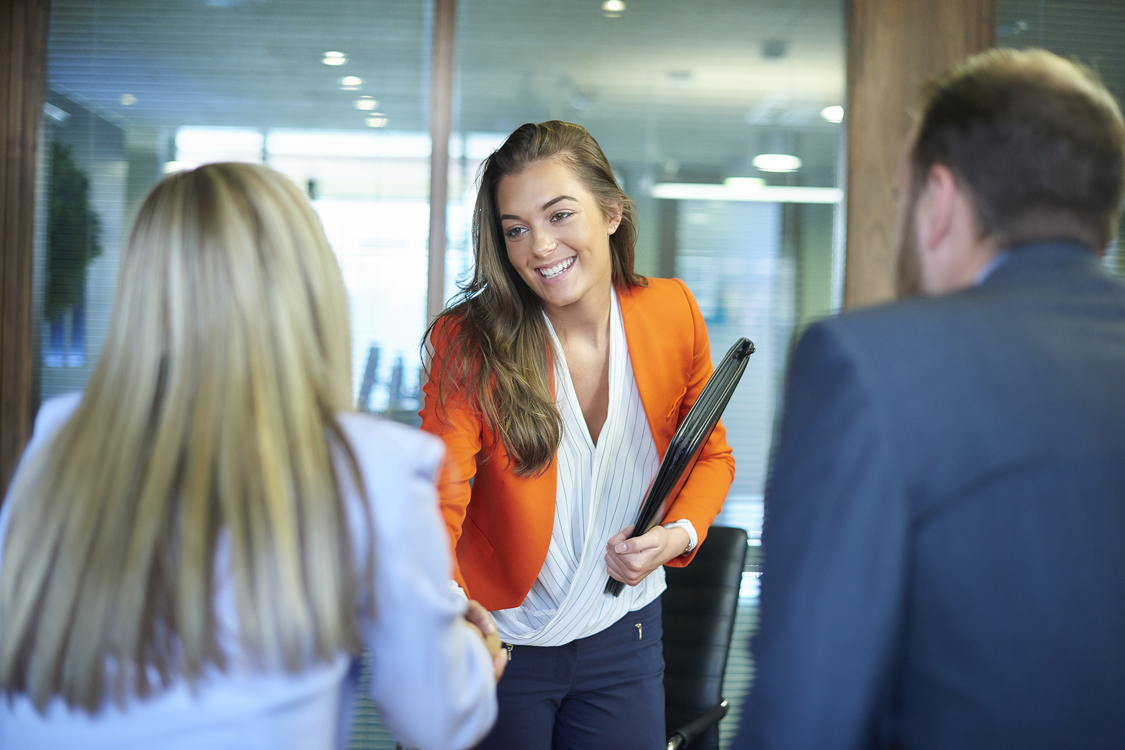 woman shaking hands with two other office workers