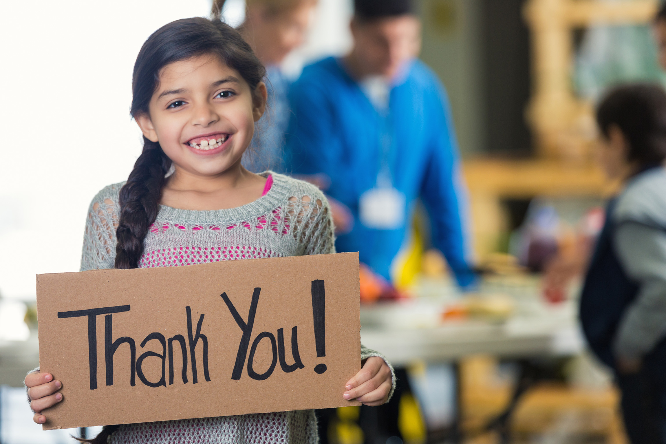 girls smiling holding a sign that says, "thank you"