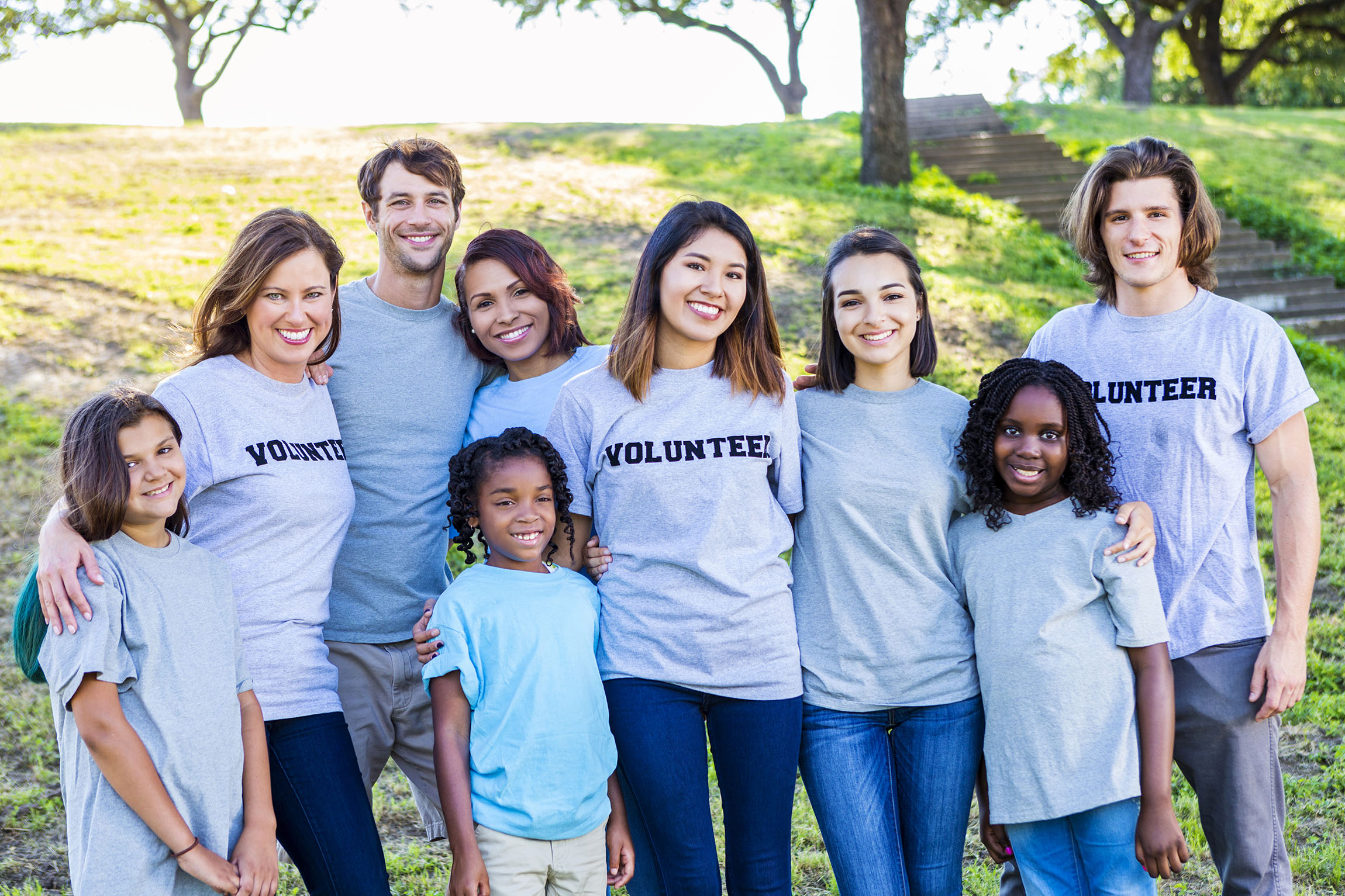 goup of children and young adults wearing volunteer shirts and smiling