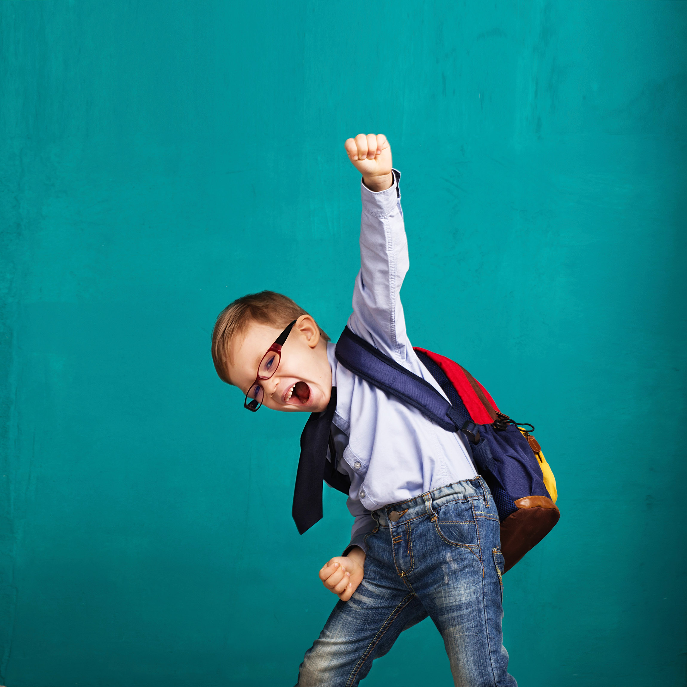 boy wearing a backpack cheering with fist in the air
