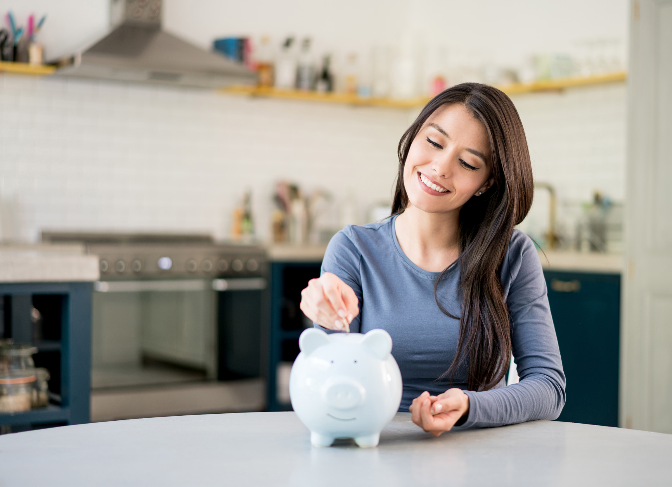 girl smiling and putting coins in a piggy bank