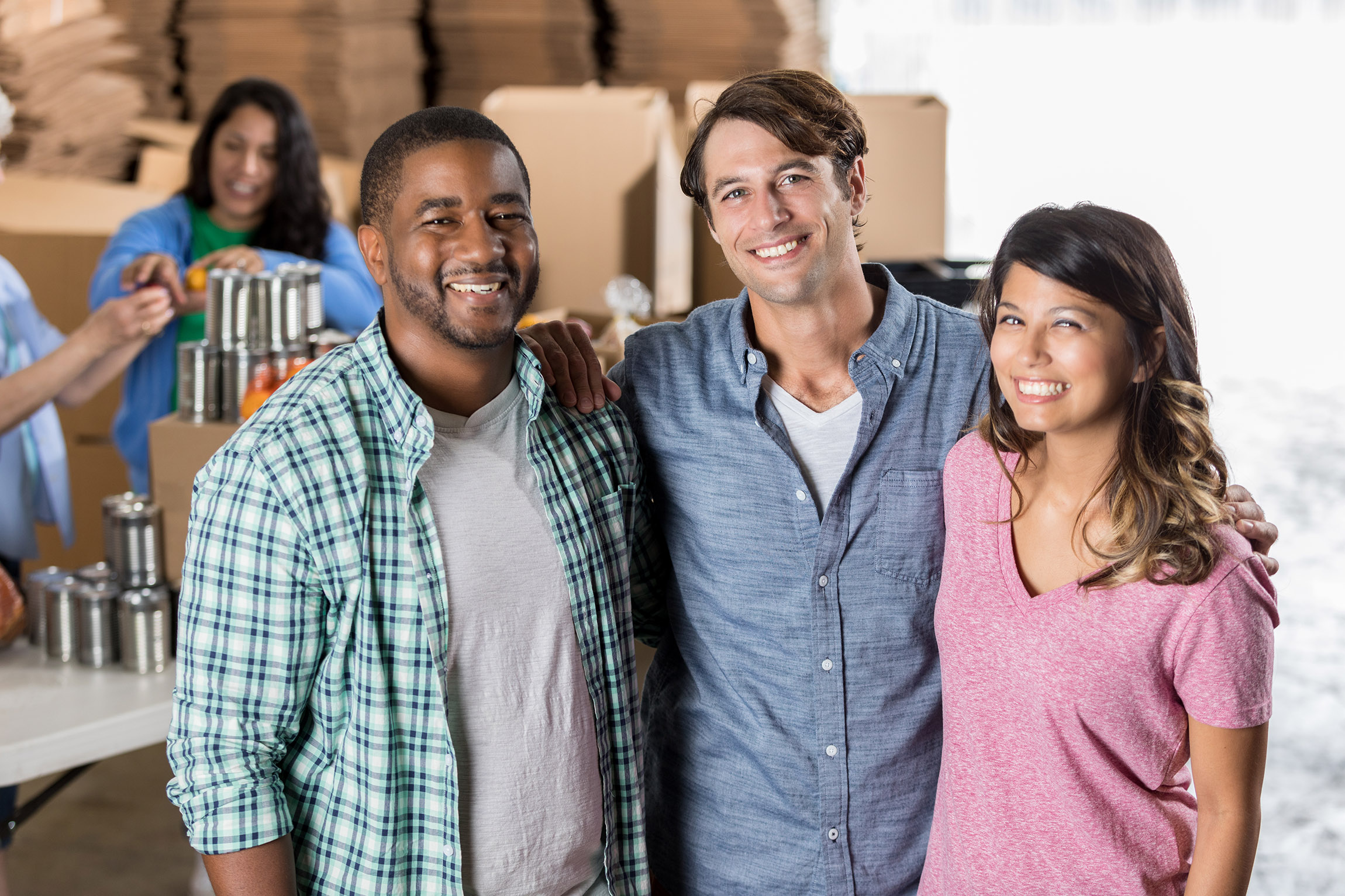 three adults posing and smiling while others work in the background