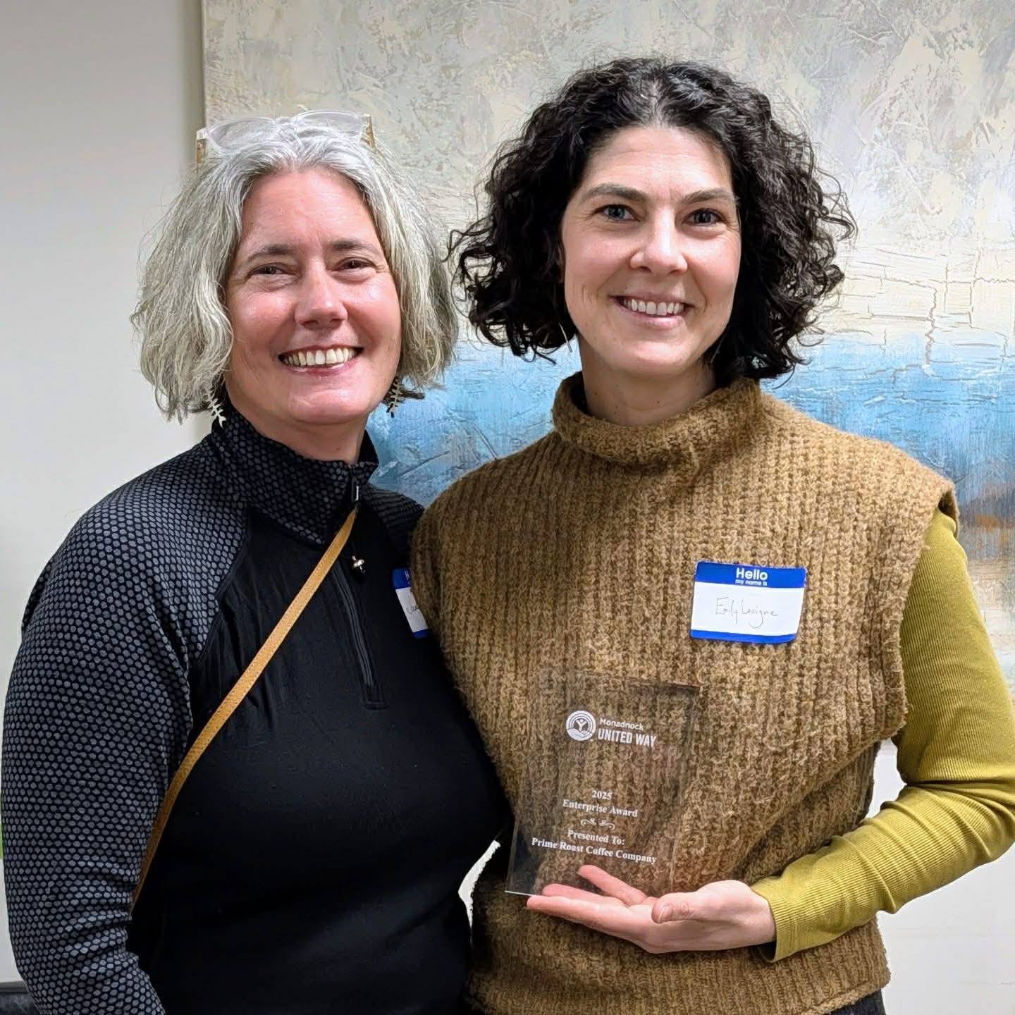 two women smiling with the award