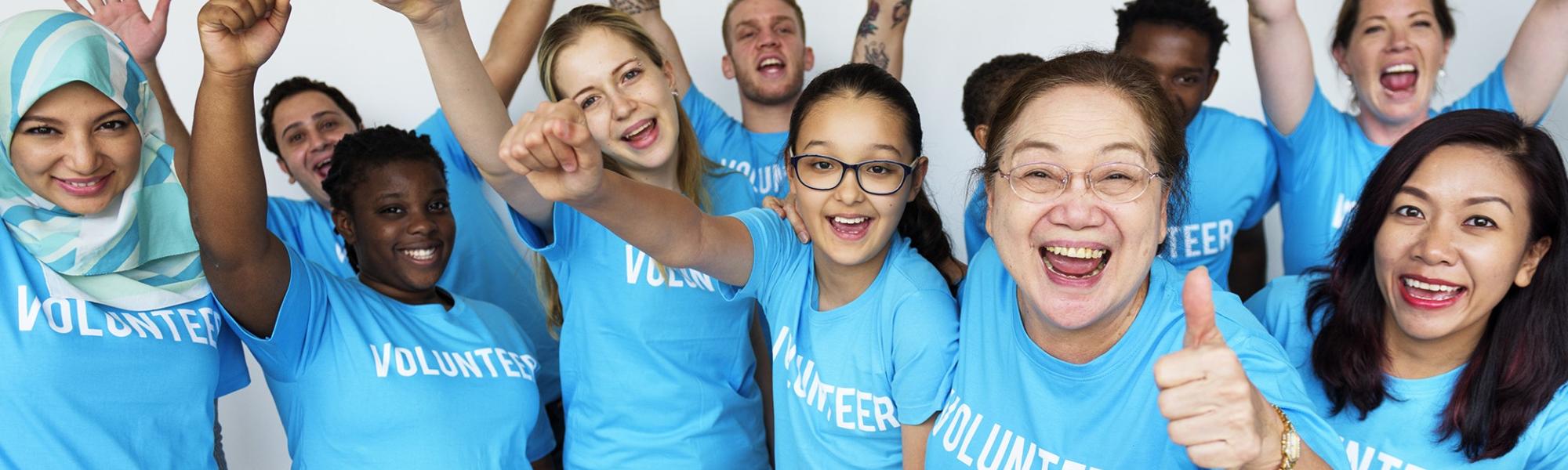 a group of people wearing volunteer t-shirts, cheering and smiling