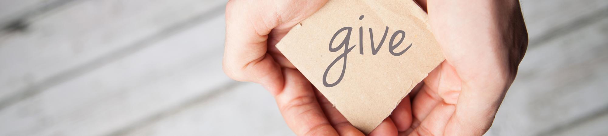 hands holding a note saying give