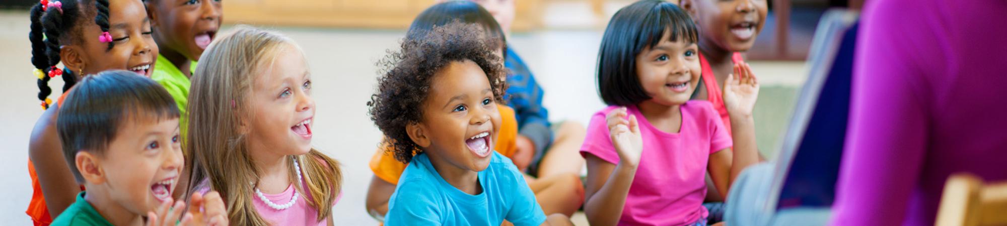 small children sitting and listening to a teacher read