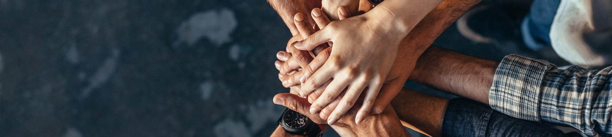 arms extended in a circle of hands signifying teamwork