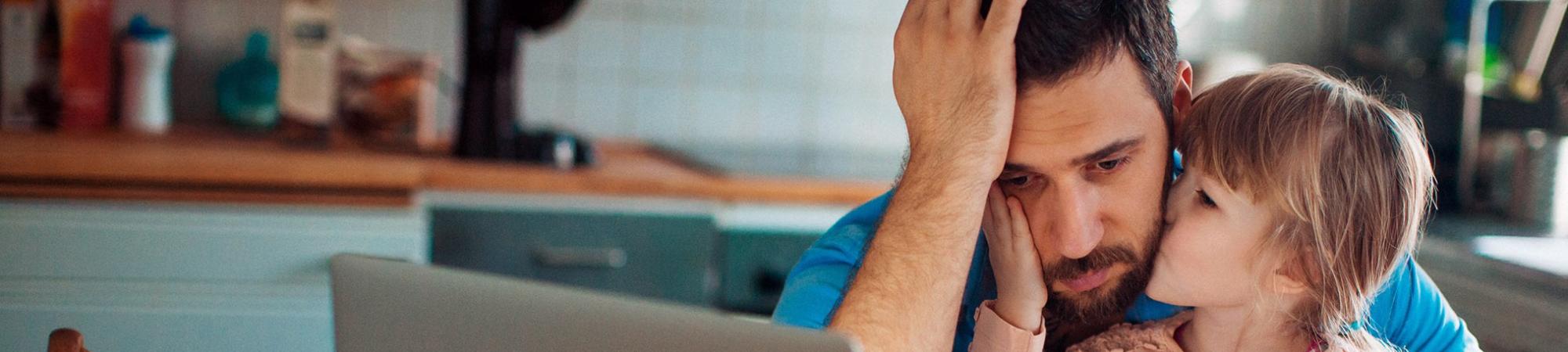daughter comforting dad as he stares despondently at a computer screen