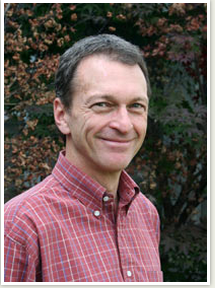 headshot of a man  in a red checked shirt smiling
