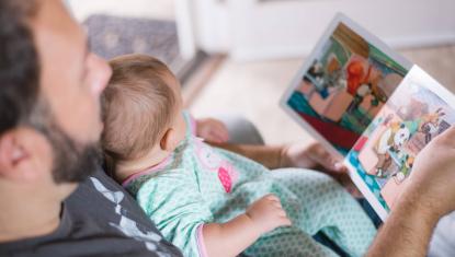 man reading a book to baby