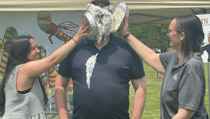 2 women hitting a man in the face with pie