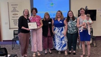 six smiling women and one baby receiving an award